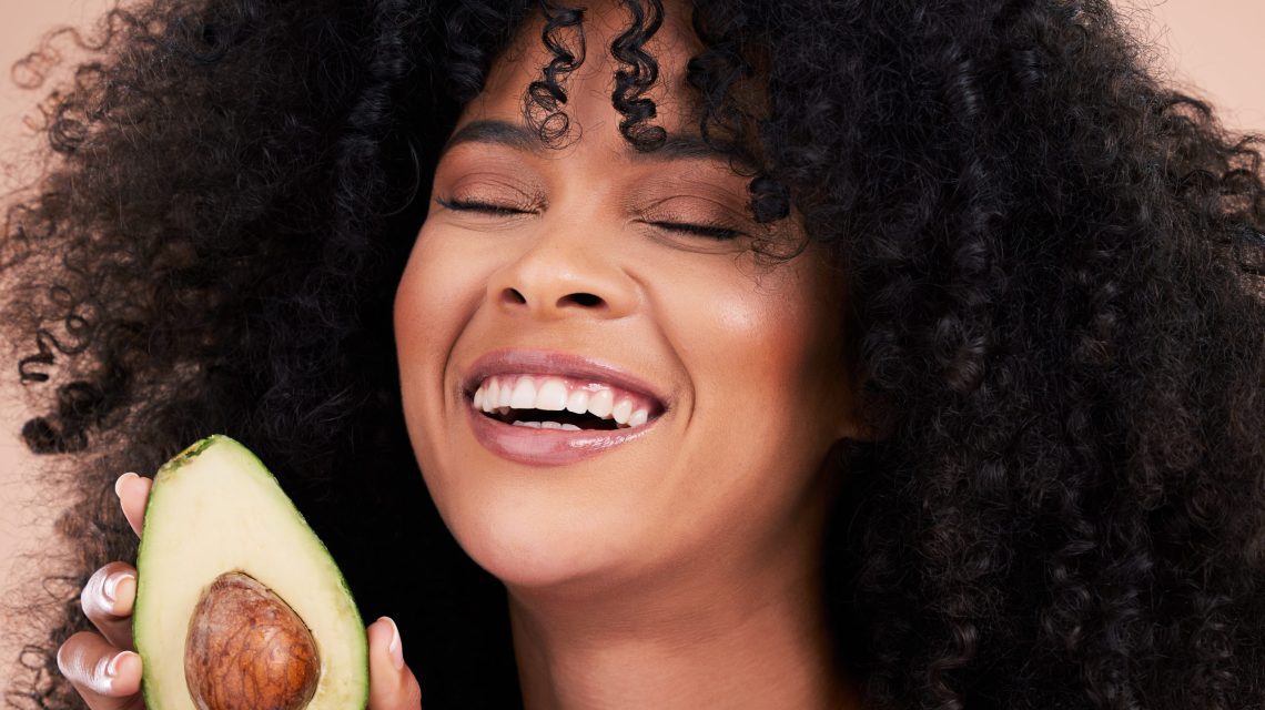 Black woman, studio and avocado for beauty, smile and skincare with health, wellness and self care .